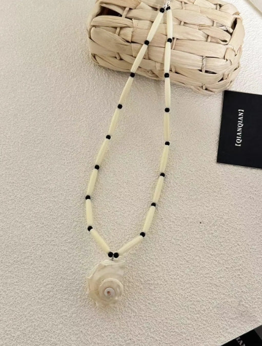 Handcrafted white conch pendant with a black and white chain design, featuring a classic and minimalist aesthetic. It's a perfect gift