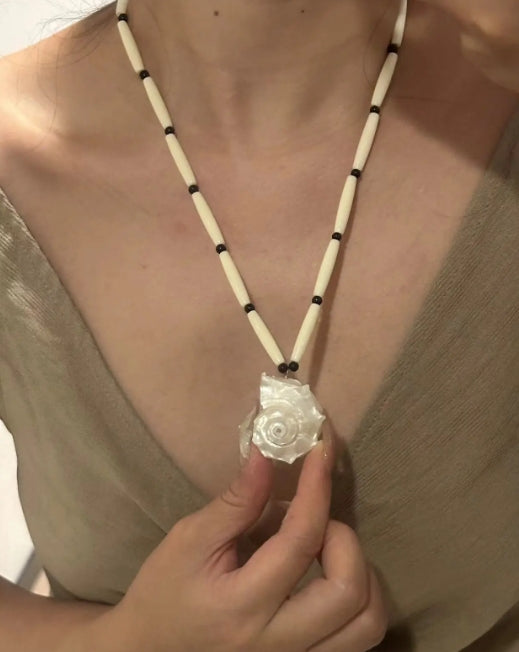Handcrafted white conch pendant with a black and white chain design, featuring a classic and minimalist aesthetic. It's a perfect gift