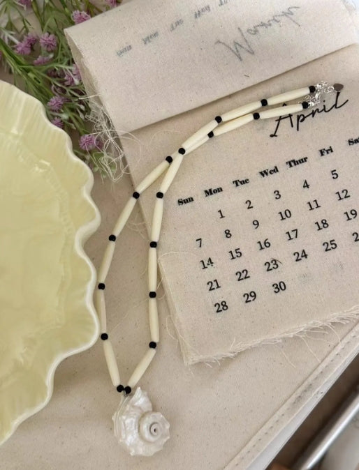 Handcrafted white conch pendant with a black and white chain design, featuring a classic and minimalist aesthetic. It's a perfect gift