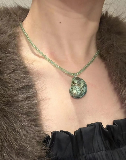 Handcrafted green conch pendant paired with a green beaded necklace, incorporates marine elements and boasts a unique design, perfect gift