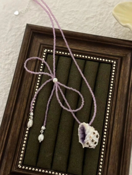 Handcrafted with natural purple conch shells, paired with a purple bow and purple beaded chain, unique and elegant aesthetic,a perfect gift