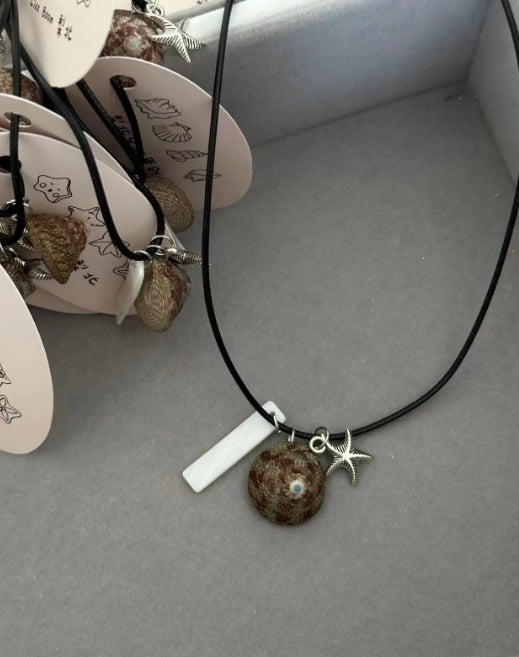 Handcrafted necklace with a natural shell pendant and a silver starfish charm, designed with a minimalist approach. It's a perfect gift