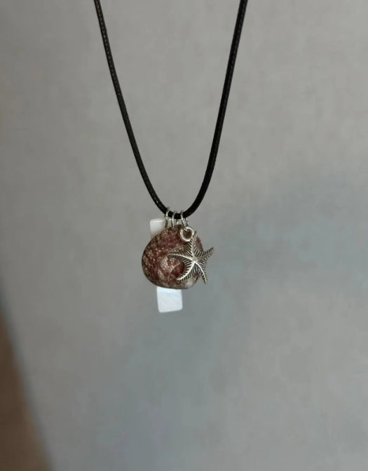 Handcrafted necklace with a natural shell pendant and a silver starfish charm, designed with a minimalist approach. It's a perfect gift