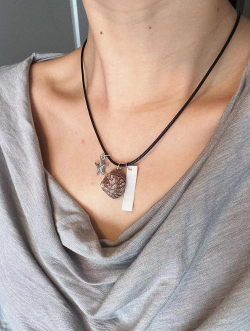 Handcrafted necklace with a natural shell pendant and a silver starfish charm, designed with a minimalist approach. It's a perfect gift