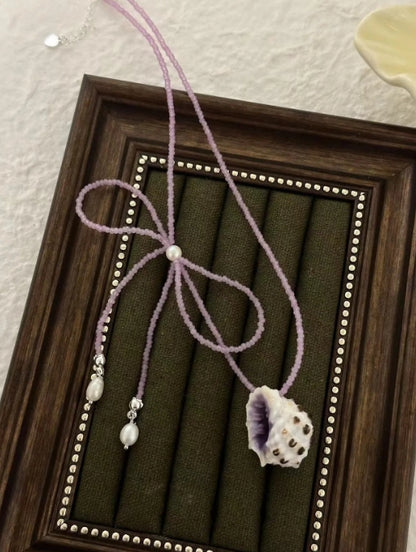 Handcrafted with natural purple conch shells, paired with a purple bow and purple beaded chain, unique and elegant aesthetic,a perfect gift