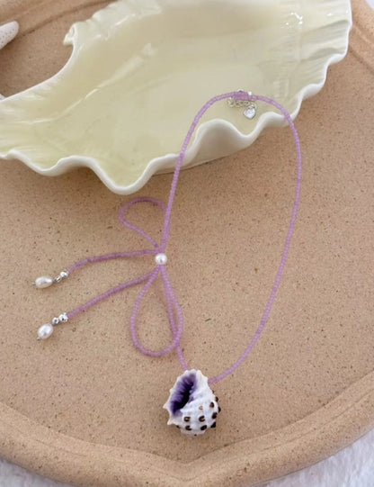 Handcrafted with natural purple conch shells, paired with a purple bow and purple beaded chain, unique and elegant aesthetic,a perfect gift